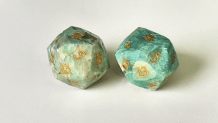Two natural blue-green Amazonite DND D20 dice engraved with the "Key of Life" pattern are spinning. | Bear Dice