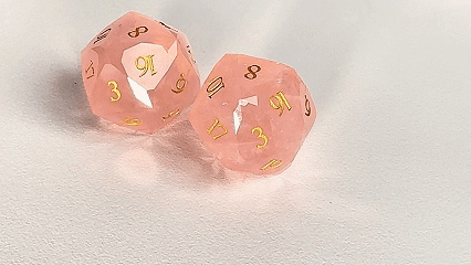 Two Natural Rose Quartz DND D20 Dice Engraved with The Gift of the Nile are spinning. | Bear Dice