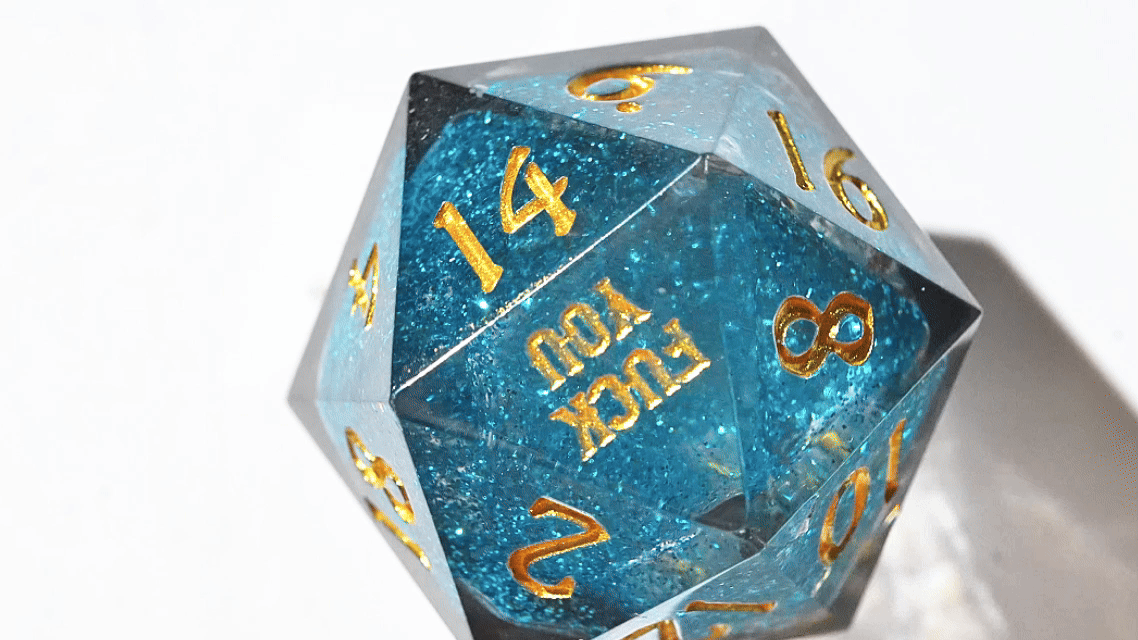 Kickstarter Dice - FUCK YOU resin DND D20 die (with gold engraved numbers) spinning on a white turntable and its blue shimmering liquid core flowing | Bear Dice