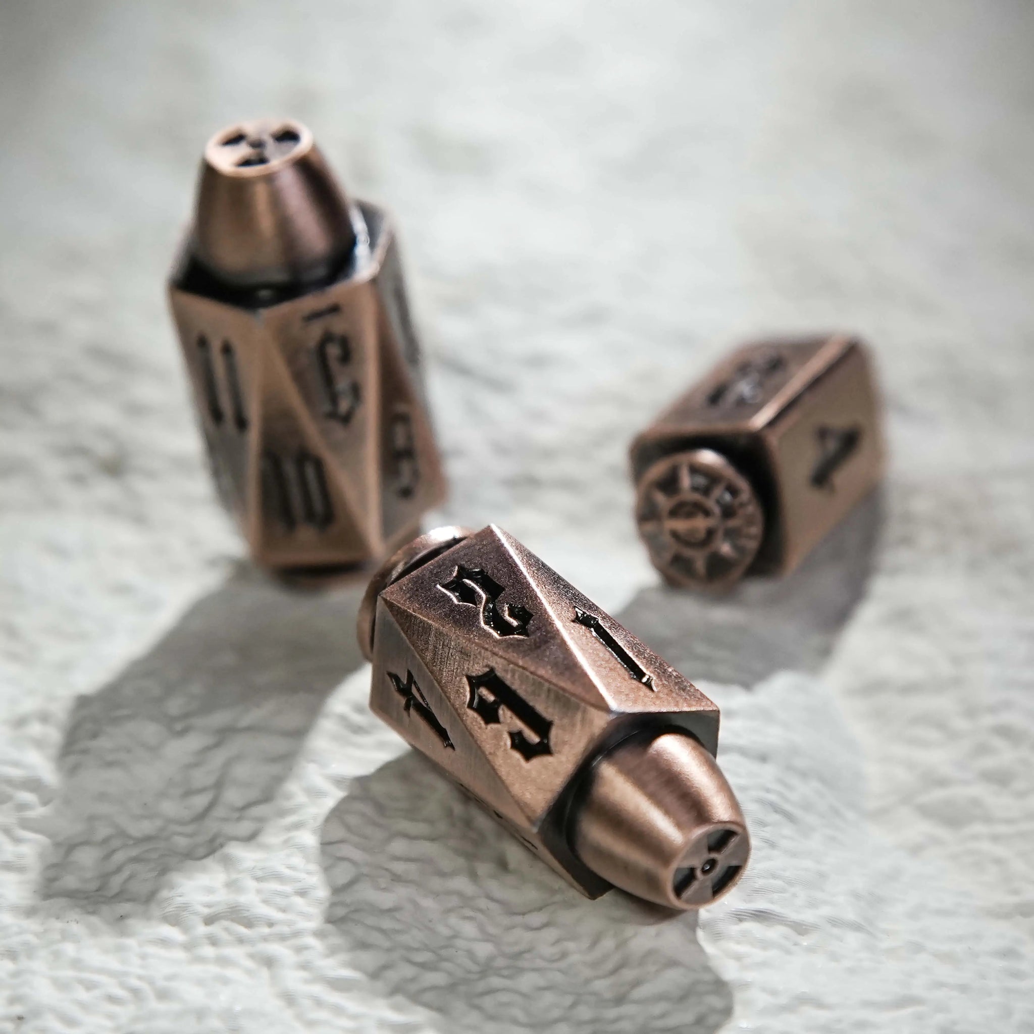 Cool Copper Polyhedron DND Metal Bullet Dice Set scattered on a white table. Bullet-shaped RPG dice | Bear Dice