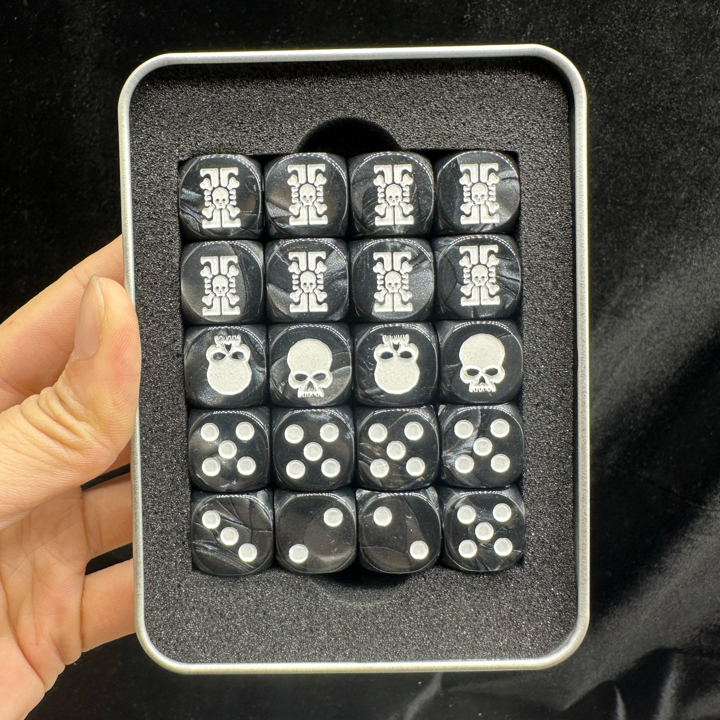 Warhammer 40K Deathwatch Acrylic D6 Dice Set of 20 — Hand-Held Official Warhammer Tin Box Top View Showing Skull-Gear Badge, Skull and White Pip Faces Arranged in Foam Insert | Bear Dice