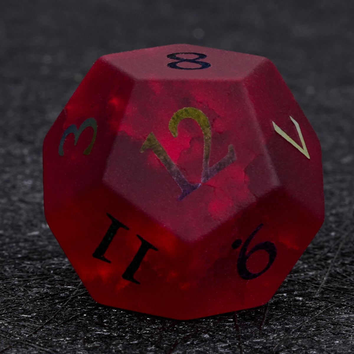 Garnet red frosted glass D12 die with rainbow-plated numbers, photographed against a black background