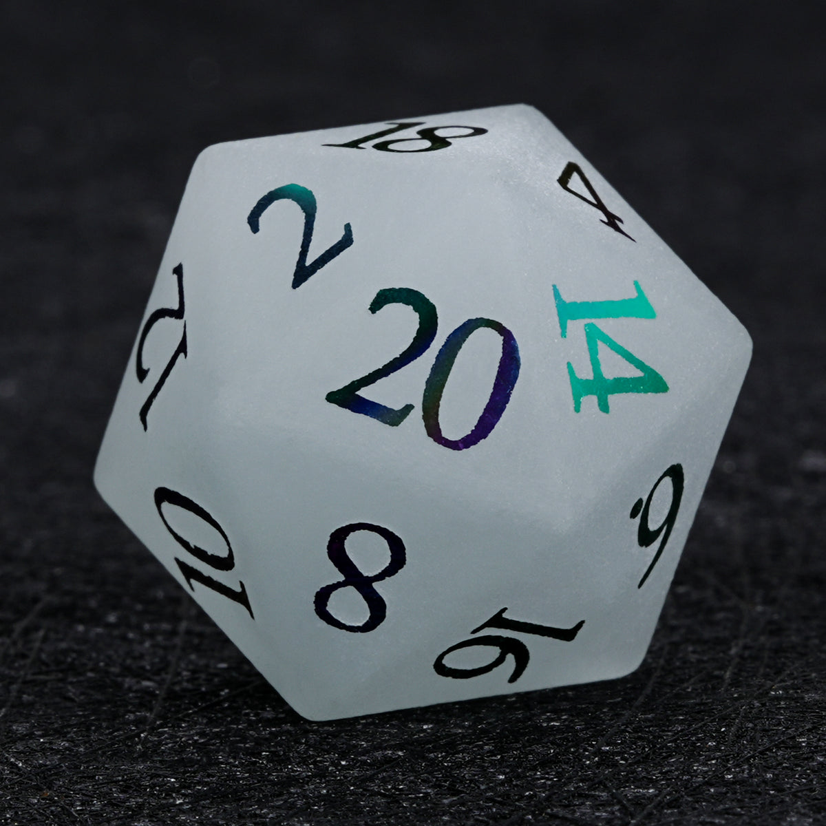 Gray frosted gemstone D20 die with multicolored electroplated numbers, shown close up on a black surface.