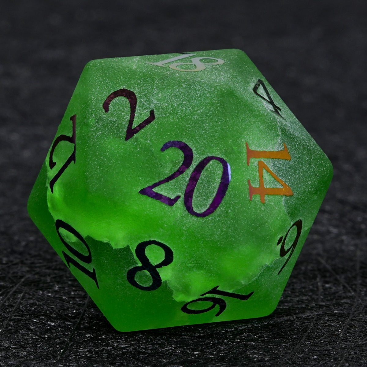 Green crackle frosted glass D20 die with multicolored electroplated numbers, shown close up on a black surface.