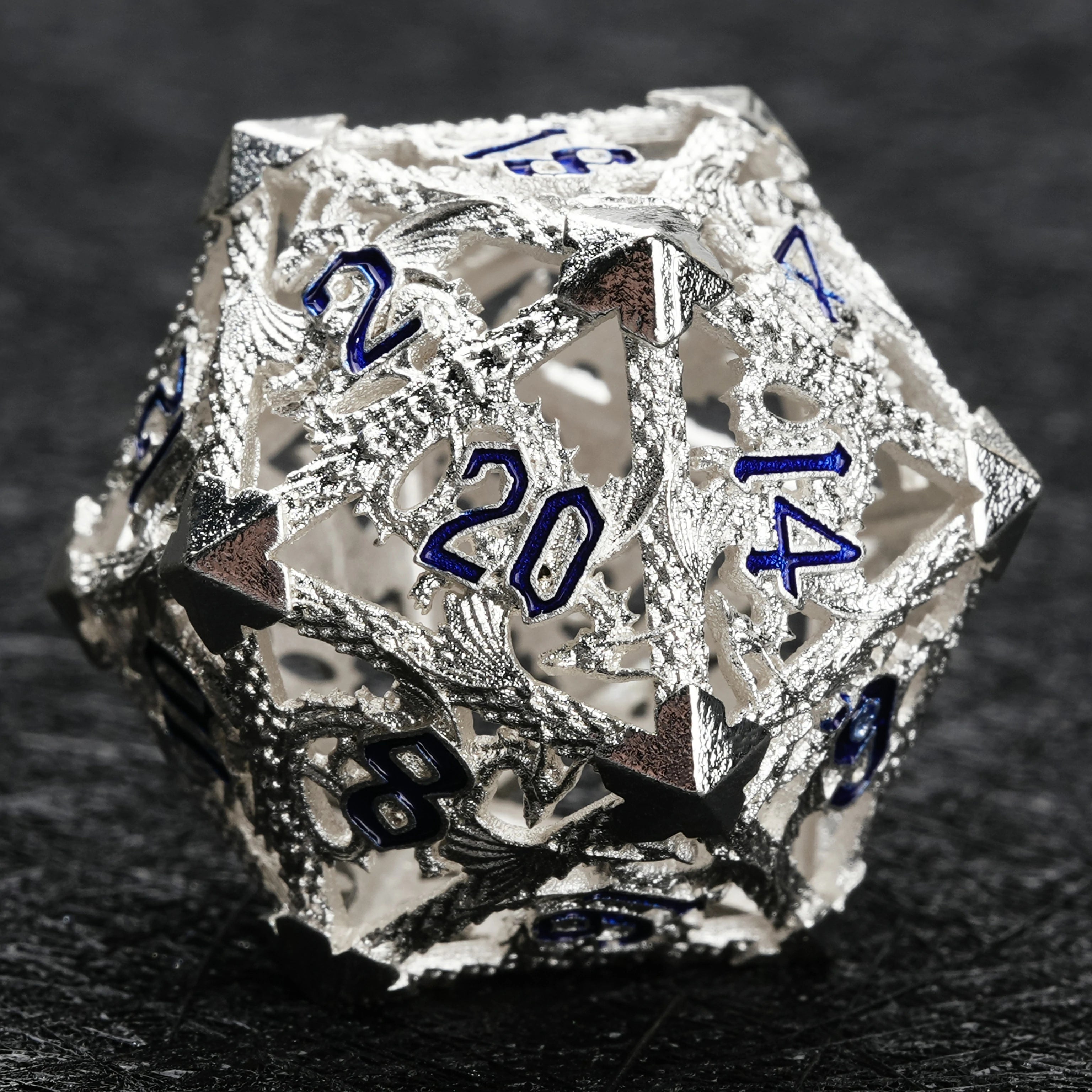 Silver hollow dragon metal D6 dice close-up showing dragon engraving and blue enamel
