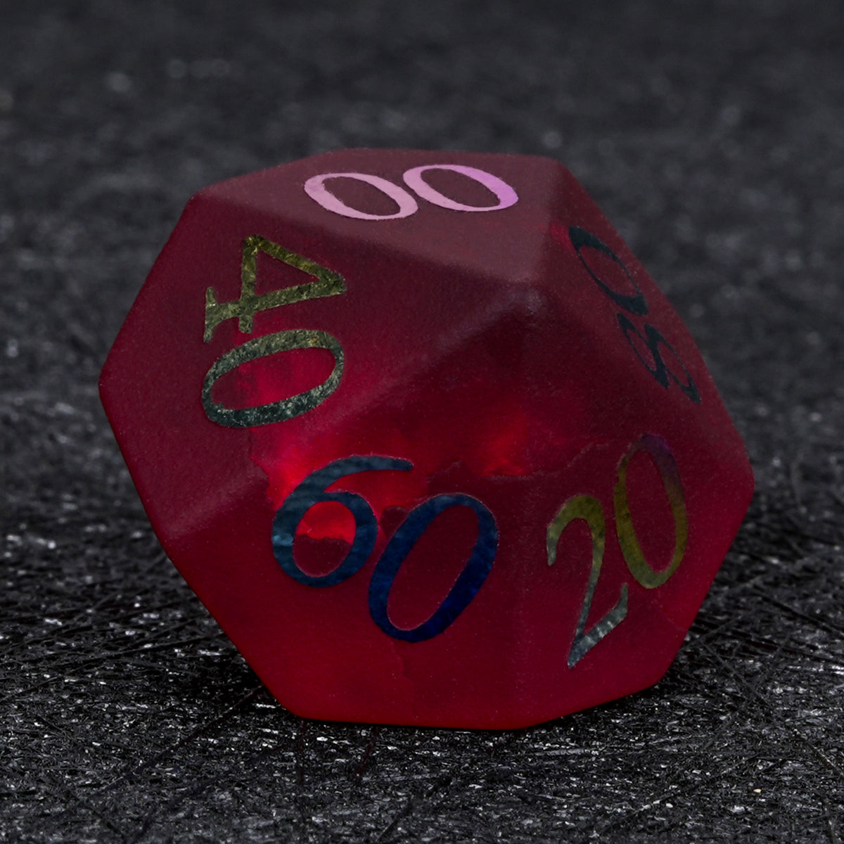 Garnet red frosted glass D100 percentile die with rainbow-plated tens markings, shown on a dark textured surface