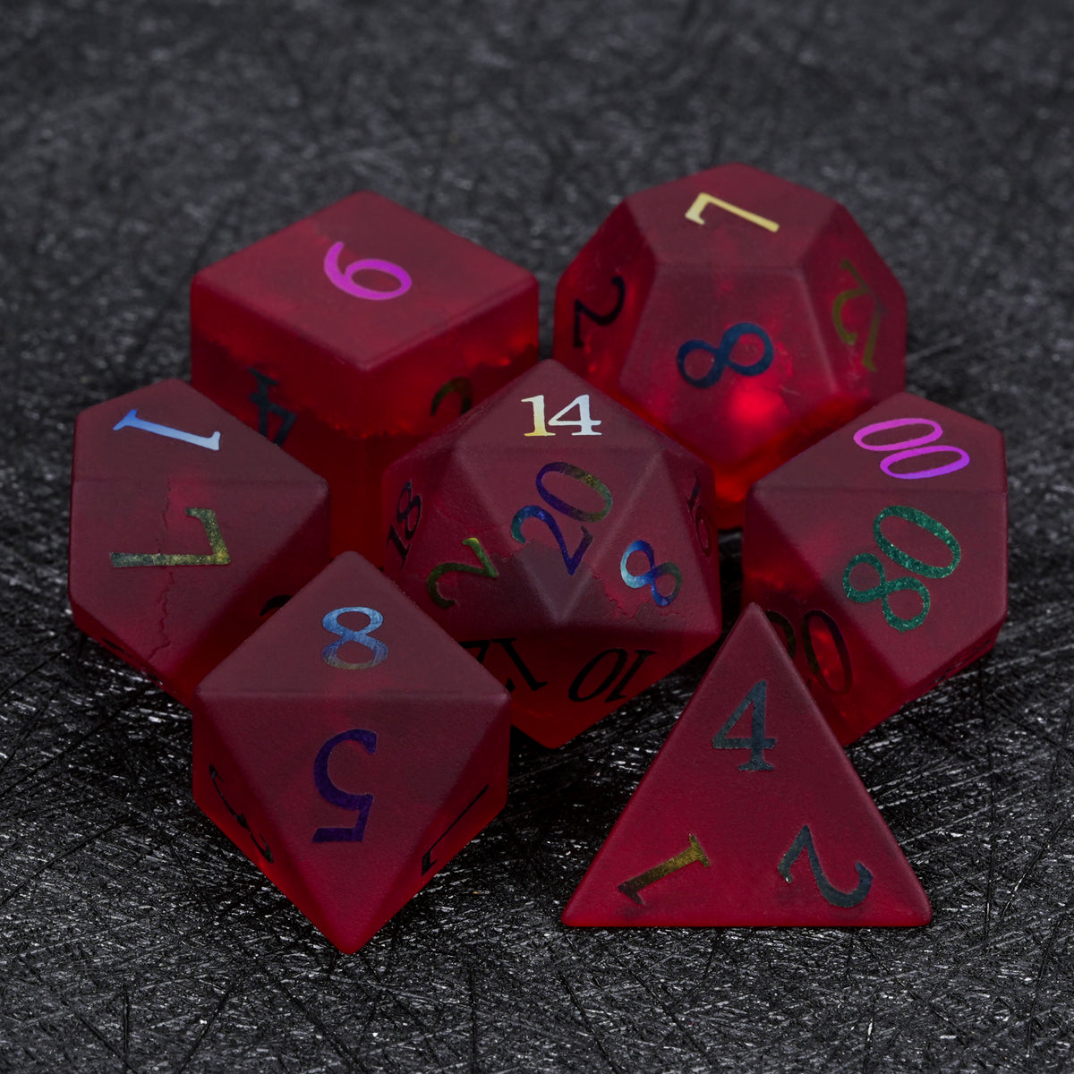 Seven-piece garnet red frosted glass dice set with rainbow-plated numbers, including D4, D6, D8, D10, D100, D12, and D20