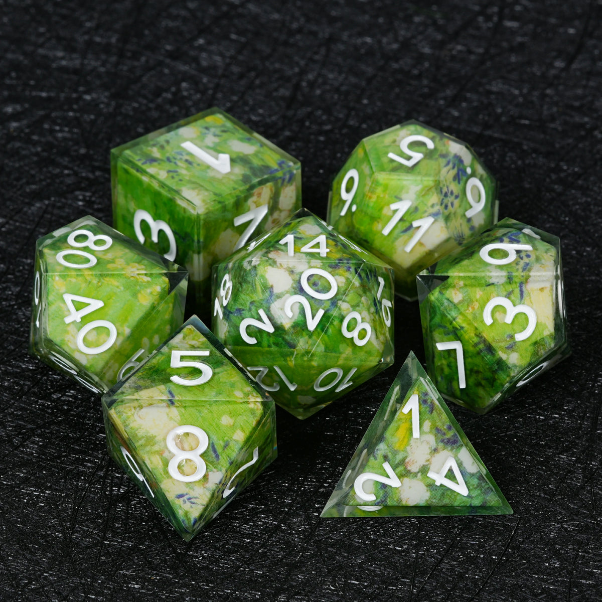 Seven green floral resin dice with white numbers, including D4, D6, D8, D10, percentile die, D12 and D20