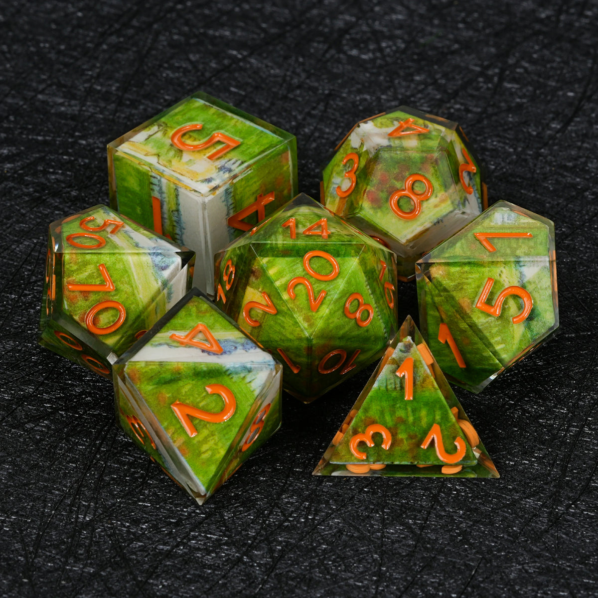 Seven green landscape resin dice with orange numbers, including D4, D6, D8, D10, percentile die, D12 and D20