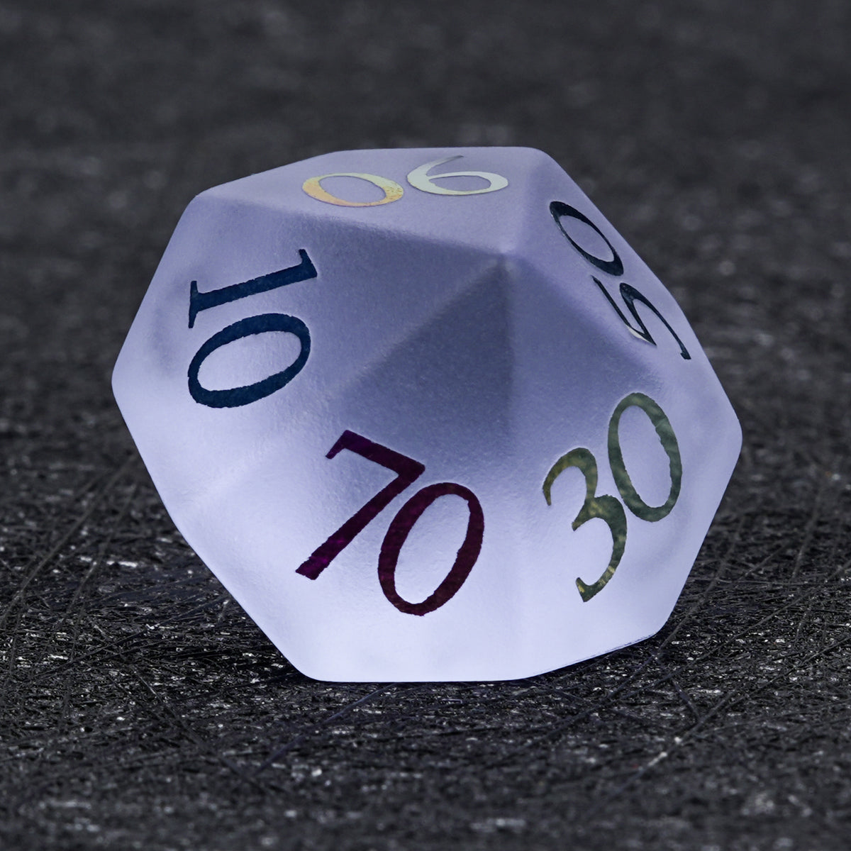 Lavender gemstone D100 percentile die with multicolored tens markings, including 70 and 90, on a dark textured surface