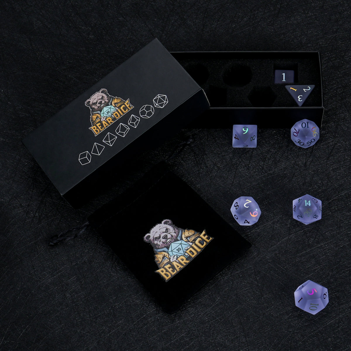 Lavender gemstone dice displayed beside black Bear Dice packaging boxes on a dark surface