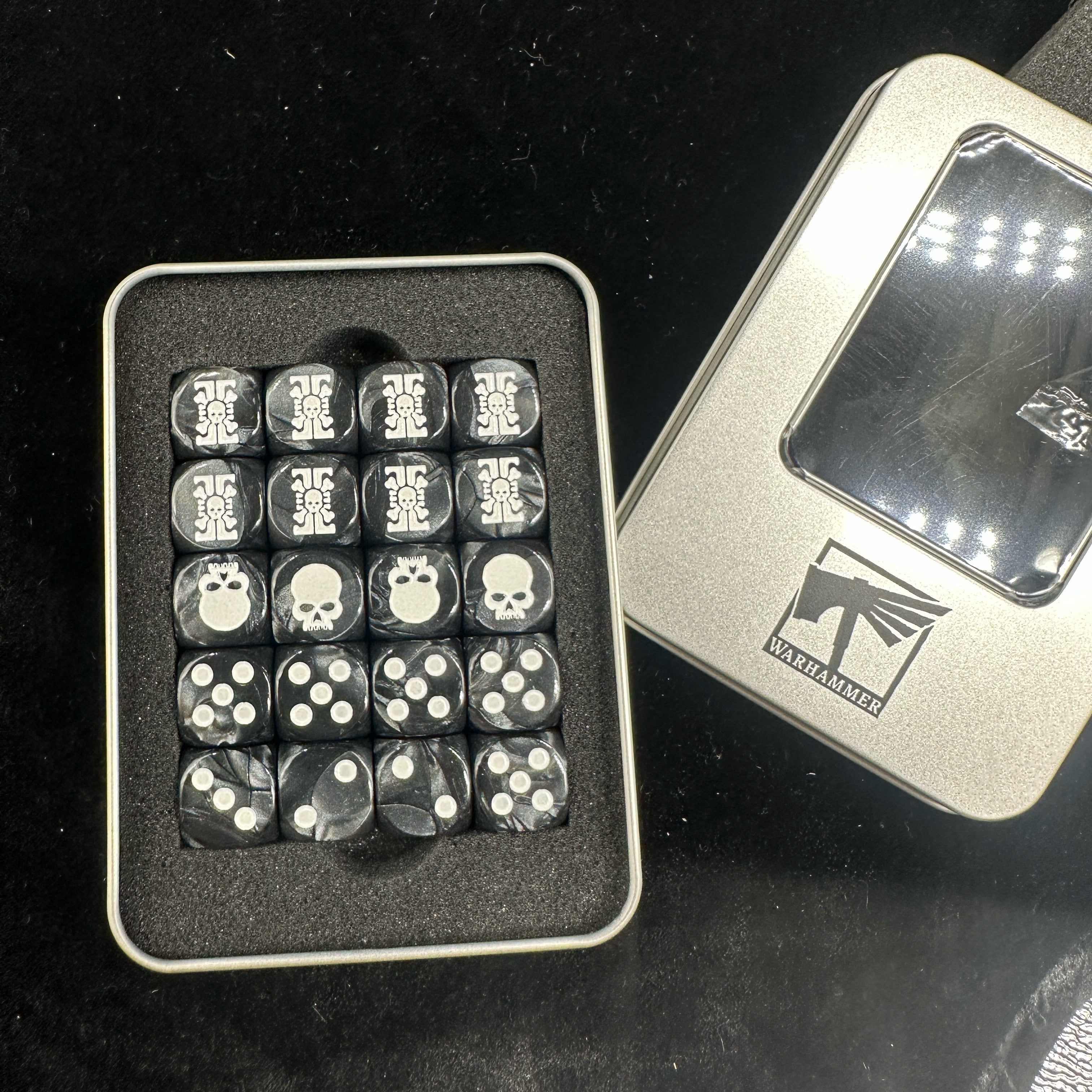 Warhammer 40K Deathwatch Acrylic D6 Dice Set of 20 — Top View in Open Official Warhammer Silver Tin Box Showing Skull-Gear Badge, Skull and White Pip Faces in Foam Insert | Bear Dice
