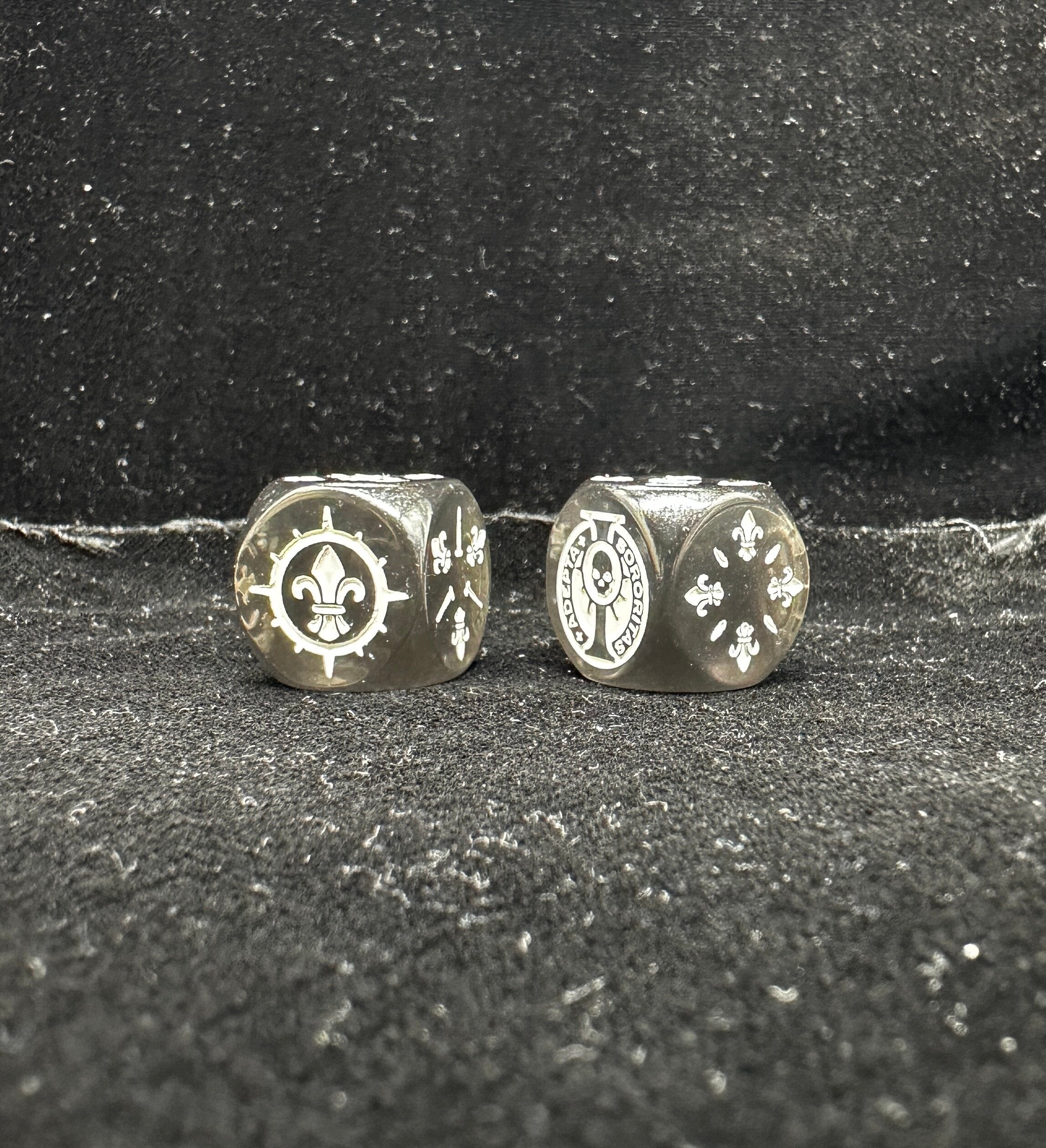 Warhammer 40K Sisters of Battle Acrylic D6 Dice — Two Dice Side by Side Close-Up Showing Thorn-Ring Fleur-de-lis 6-Face and Adepta Sororitas Inscription 5-Face on Smoky Transparent Acrylic Body | Bear Dice